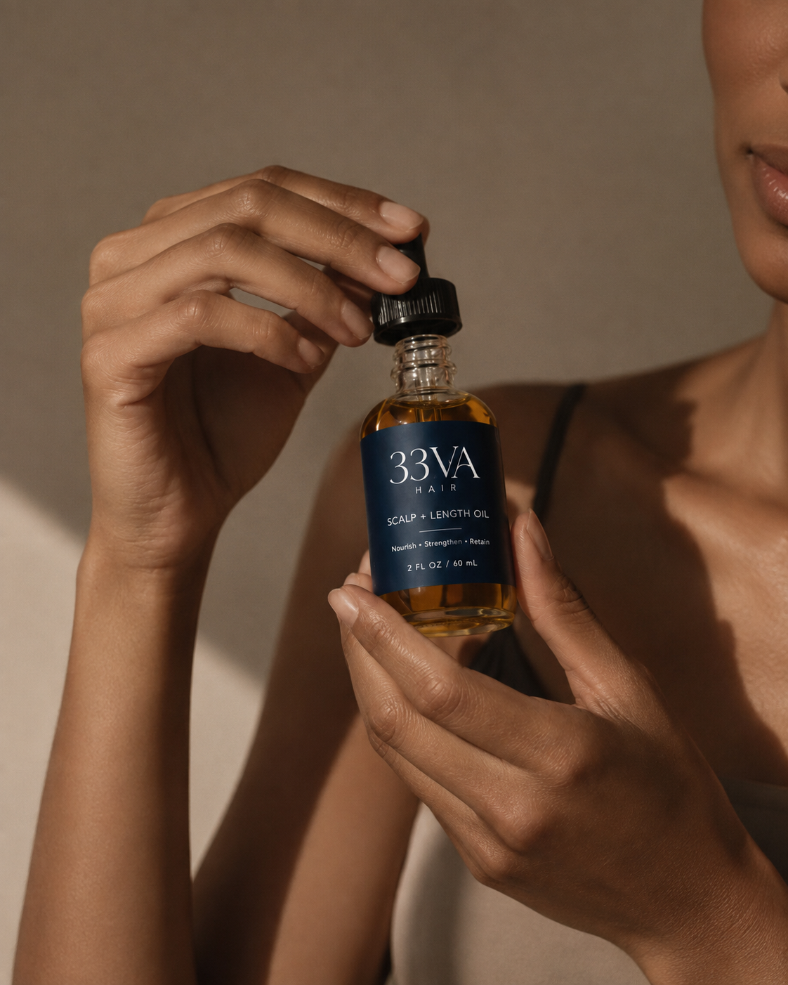 A person holding 33VA Scalp & Length Oil bottle